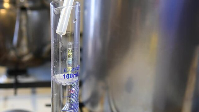 Measuring the degrees of moonshine with an alcoholometer in a glass flask. Production of strong vodka at home.