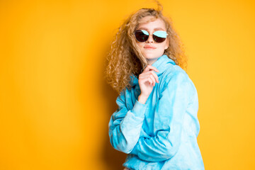 Beautiful woman in a sweater with glasses pulls back a lock of her curly hair