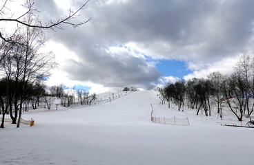 Empty ski slope front view on overcast winter day at ski resort in low season