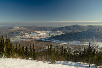 the landscape of a ski resort, in the distance you can see the city located in the lowlands of the mountains