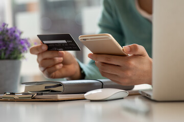 Online payment,Young Woman's hands holding smartphone and using credit card laptop for online shopping. Cyber Monday Concept