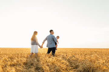 Happy family in wheat field at sunset having a great time together