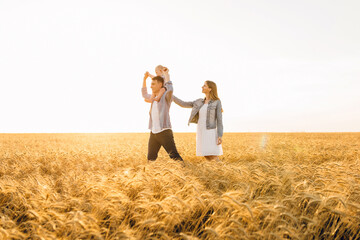 Happy family on a summer walk, mother, father and child walk in the wheat