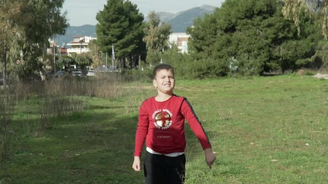 Slow motion shot of caucasian boy making a pass with a basketball towards the camera, playing in the fields near partita mountain, Athens, Greece