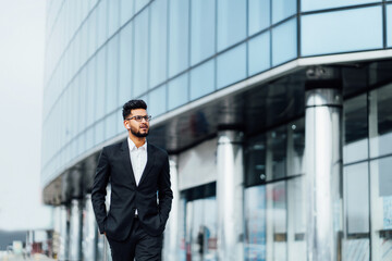 A modern Indian man goes to a business meeting, behind him a modern building, an office, a successful modern Indian man