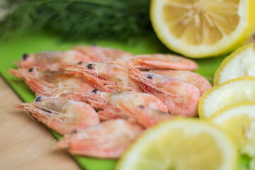 shrimps on a green board with lemon and dill