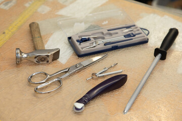 Shoemaker hammer tool, circle, scissors and a measure tape on a desk. Symbolic for craftsman and their workplace.