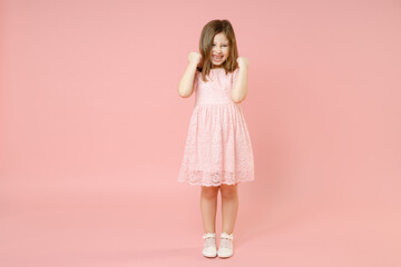 Full length little cute kid girl 5-6 years old wears rosy dress have fun standing isolated on pastel pink background child studio portrait. Mother's Day love family people childhood lifestyle concept.