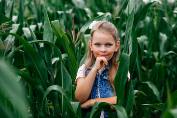 Stylish young girl 8-10 years old in stylish clothes posing in a corn field. Unity with nature. Caring for the environment, peace of mind in the countryside. Fashion concept
