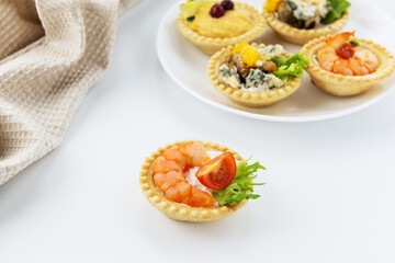 Tartlet with shrimp, tomato and cheese on the background of a set of tartlets.
