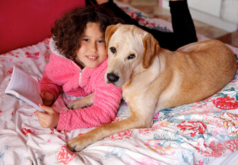A child with a dog on the bed.