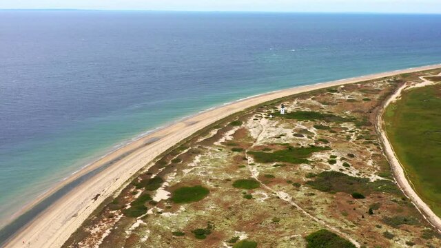 Aerial shot of lighthouse at beach against sky on sunny day, drone flying forward over coastline - Cape Cod, Massachusetts