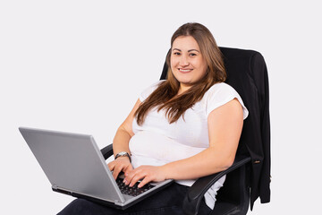 Naklejka premium Caucasian woman working on laptop sitting in office. Overweight young woman staying at home during quarantine. Self isolation. Working distantly from home using laptop.