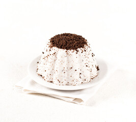 Vanilla panna cotta with chocolate chip cookie crumbs on a plate on a white background