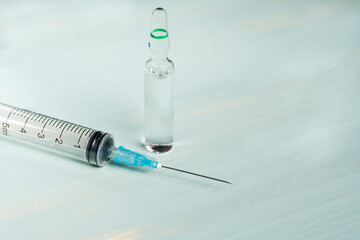 Medical ampoule and syringe isolated on green background, vaccination concept and disease treatments