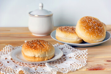 Fresh burger buns with sesame on wooden table.