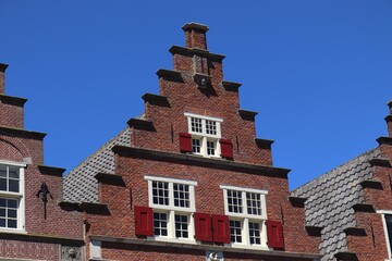 Historic Dutch House Facade with Stepped Gable and Red Shutters in Hoorn