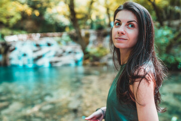 Carefree woman standing near blue waterfall