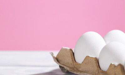 White Chicken eggs in a cardboard box on a pink background, Raw Fresh Eggs in a paper container,...