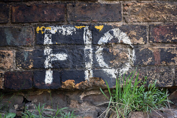 Letter & Number in Faded White Paint on Weathered Brick Wall