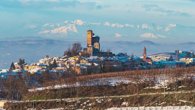 Zoom in: Italy Piedmont panoramic winter snow view wine yards unique landscape at sunset, Serralunga d'Alba medieval castle and villages on hill top, the Alps in the background dramatic sky