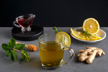 an immune ginger drink with honey and lemon in a glass cup next to the ingredients.
