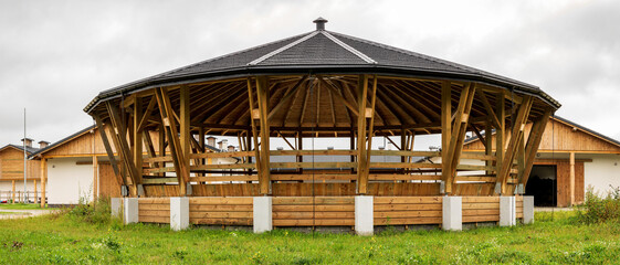 Fototapeta na wymiar Lunge ring arena for horse training outside view. Circle equestrian building with roof. Modern equestrian round pen place.