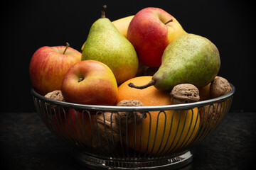 fruit bowl with apples, banana, pears, orange and walnuts