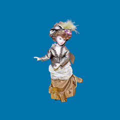 ceramic porcelain doll in vintage dress isolated on blue. Toy lady poses in old fashioned clothes. Antique old dolly