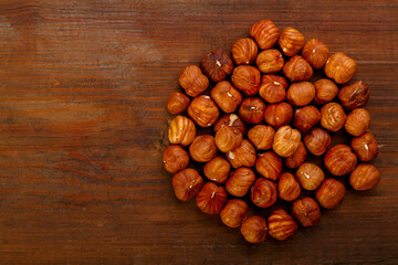 Hazelnuts are scattered on a dark wooden table.