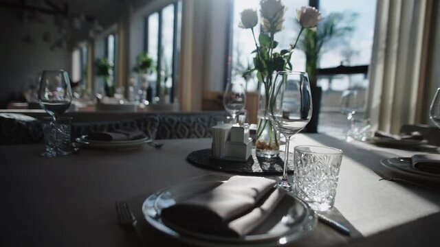 Glasses and plates on a banquet table. Night Party at a fancy restaurant.  Celebration event on holidays. Beautiful decoration with candles on tables. Gourmet and luxury dinner. Festive table setting.
