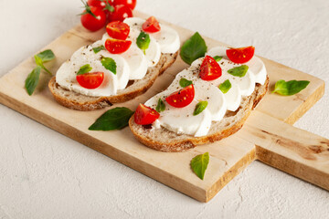 Ciabatta with cherry tomato, basil, mozzarella and spices. Bruschetta with cheese on concrete table. 