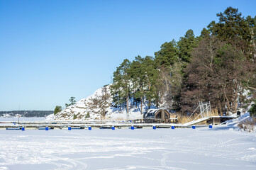 Scandinavian winter snowy landscape. Wooden bathhouse or small house cabin in the form of barrel or...