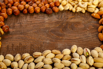 Frame of scattered assorted nuts on a wooden table. Copy space.