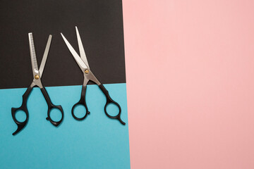 Professional hair cutting tools, scissors. Colored background blue, pink, and black.
