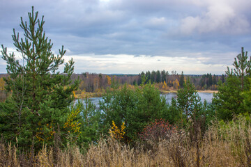Summer landscape with a beautiful lake with fir trees and forested mountains against a cloudy sky