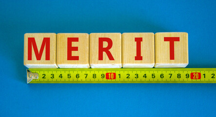 Merit symbol. Wooden cubes with the word 'merit'. Beautiful blue background, copy space. Yellow...