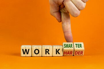 Work harder or smarter symbol. Businessman turns wooden cubes and changes words 'work harder' to 'work smarter'. Beautiful orange background, copy space. Business and work harder or smarter concept.