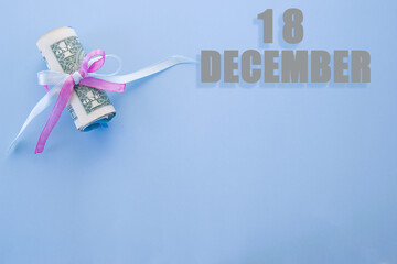 calendar date on blue background with rolled up dollar bills pinned by blue and pink ribbon with...