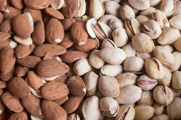 Close-up of a plate full of almonds and the other half with pistachios. Nuts and healthy eating.