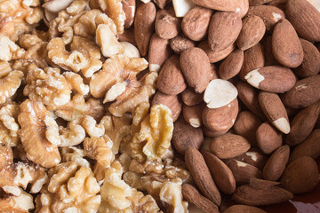 A pile of walnuts and almonds divides the image in two. Nuts and health.