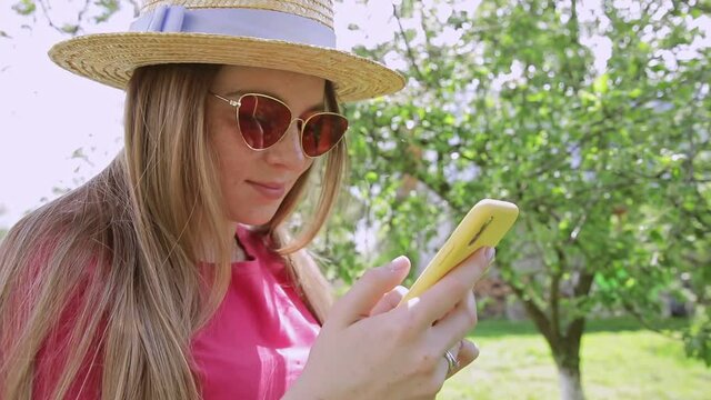 Happy girl using a smart phone on garden background. scrolling and using social media