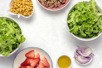 Salad with lettuce, strawberries, red onion, corn; olive oil and walnuts