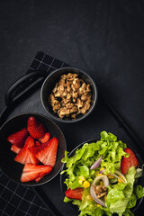 Salad with lettuce, strawberries, red onion, corn; olive oil and walnuts