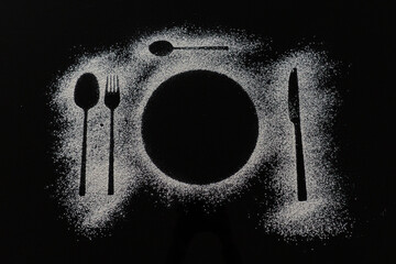 top view of cutlery and plate silhouette made with flour