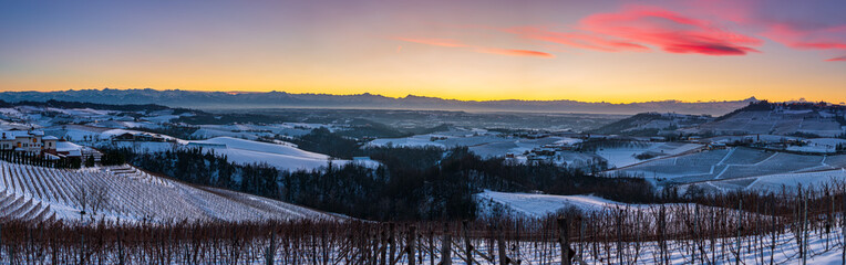 Fototapeta na wymiar Italy Piedmont: panoramic winter snow view wine yards unique landscape at sunset, medieval castle and village on hill top, the Alps in the background dramatic sky