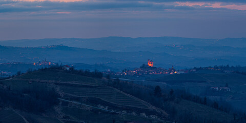 Italy Piedmont: panoramic winter snow view wine yards unique landscape at sunset, medieval castle and village on hill top, the Alps in the background dramatic sky