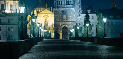 .Charles bridge. Lamps on the empty Charles Bridge on the Vltava river at night and the stone bridge tower in the center of Prague