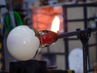 Artistic glassblower forms a work of art at the end of a glass pipe.