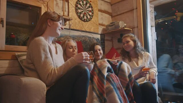 Female best friends spending winter holidays in the cozy home drinking mulled wine and having snacks. High quality 4k footage